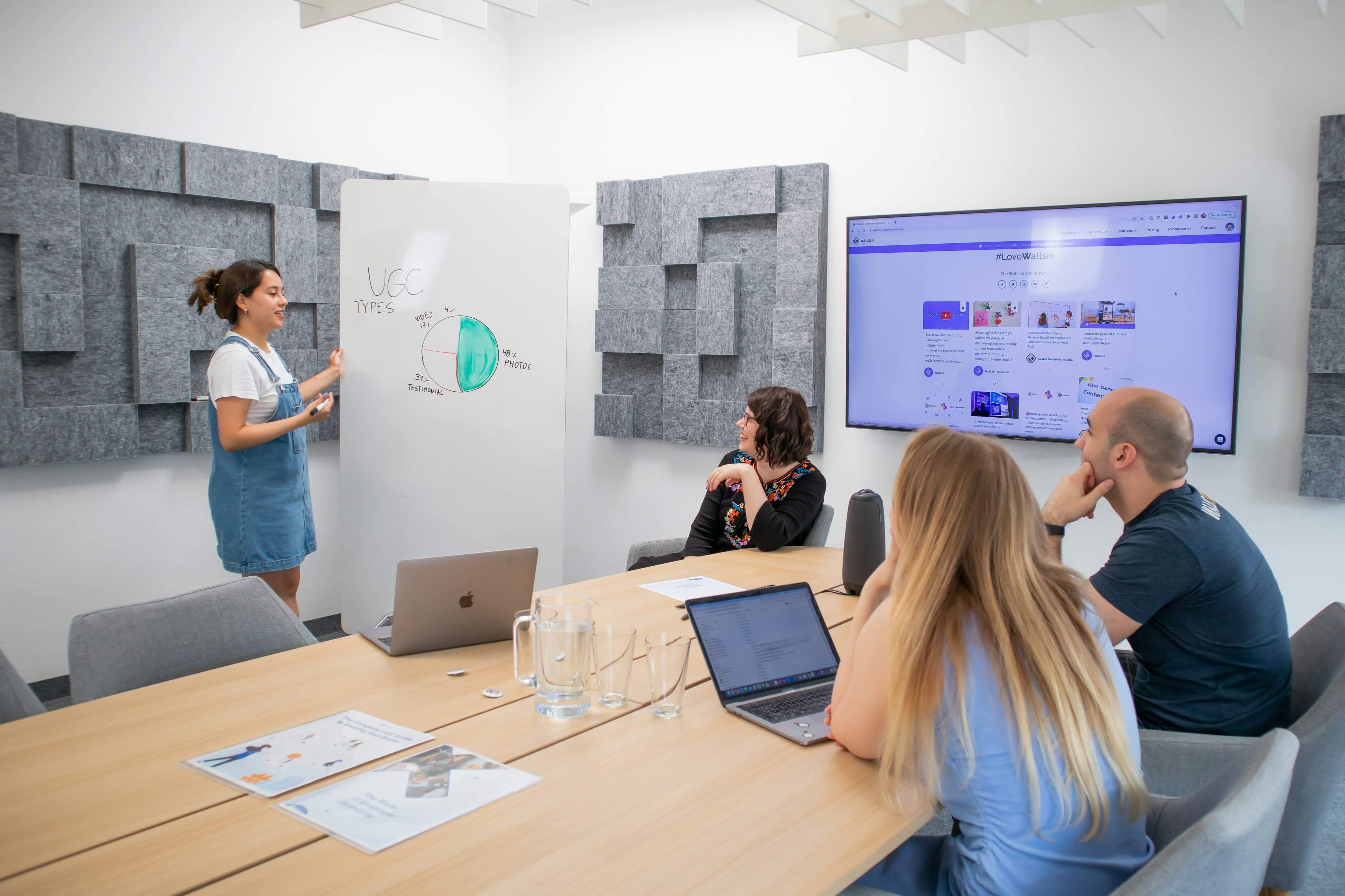 Donna che presenta dati a un team in sala riunioni, contesto di compliance aziendale e parità di genere
